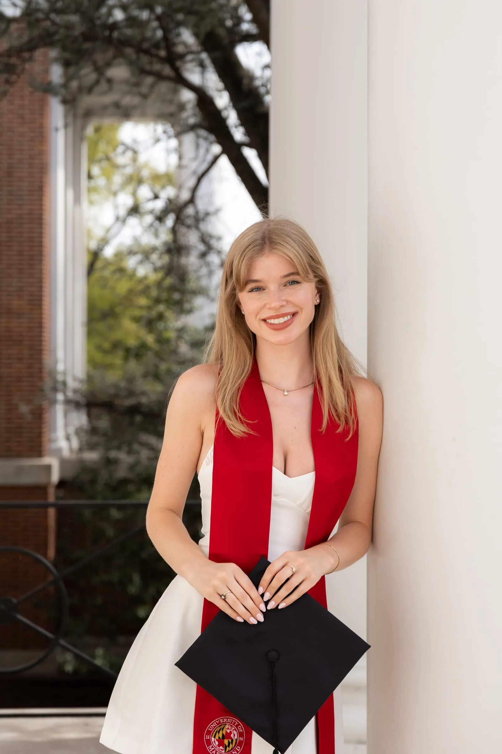 College graduate smiling between tall white pillars