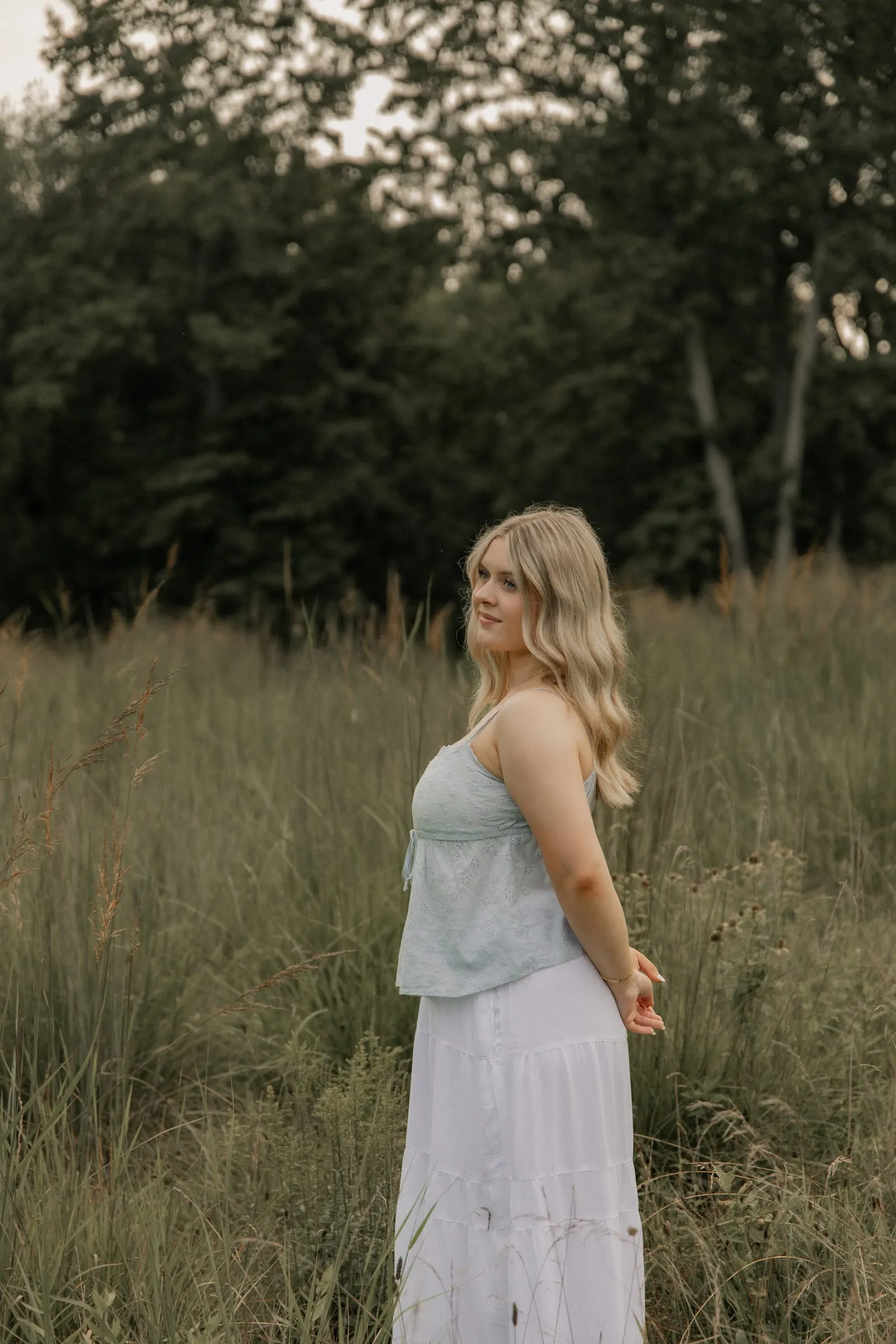 High school senior glancing back over her shoulder in a tall-grass field