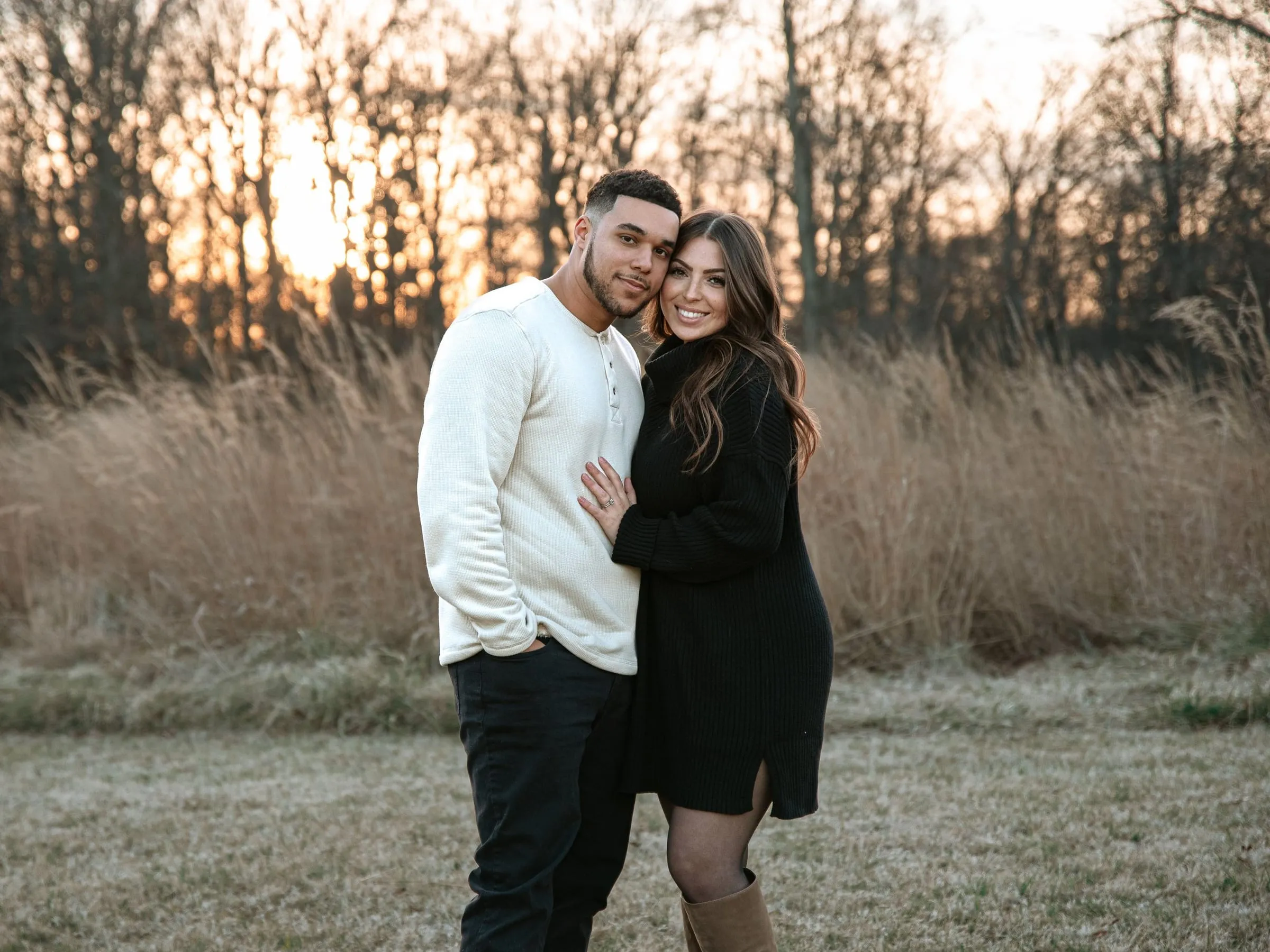 Brittany and her husband standing close in a golden winter field